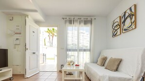 Un soggiorno con un divano, un tavolino, una TV e una porta che dà sull'esterno.