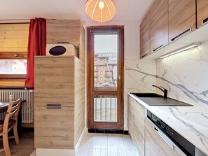 Eine moderne Küche mit Holzausstattung, einem integrierten Geschirrspüler und Blick durch eine Glastür.