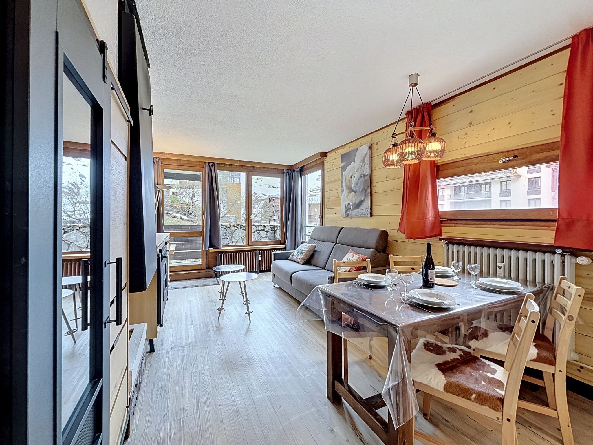 A modern interior with a dining table, chairs, a sofa, and a large window.