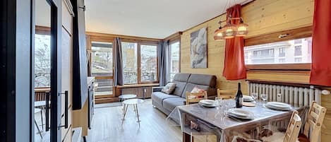 A modern interior with a dining table, chairs, a sofa, and a large window.