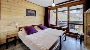 A wooden-paneled room with a bed, a window, and a bear-themed picture. - Le Pramecou (Val Claret) by Interhome (Tignes)
