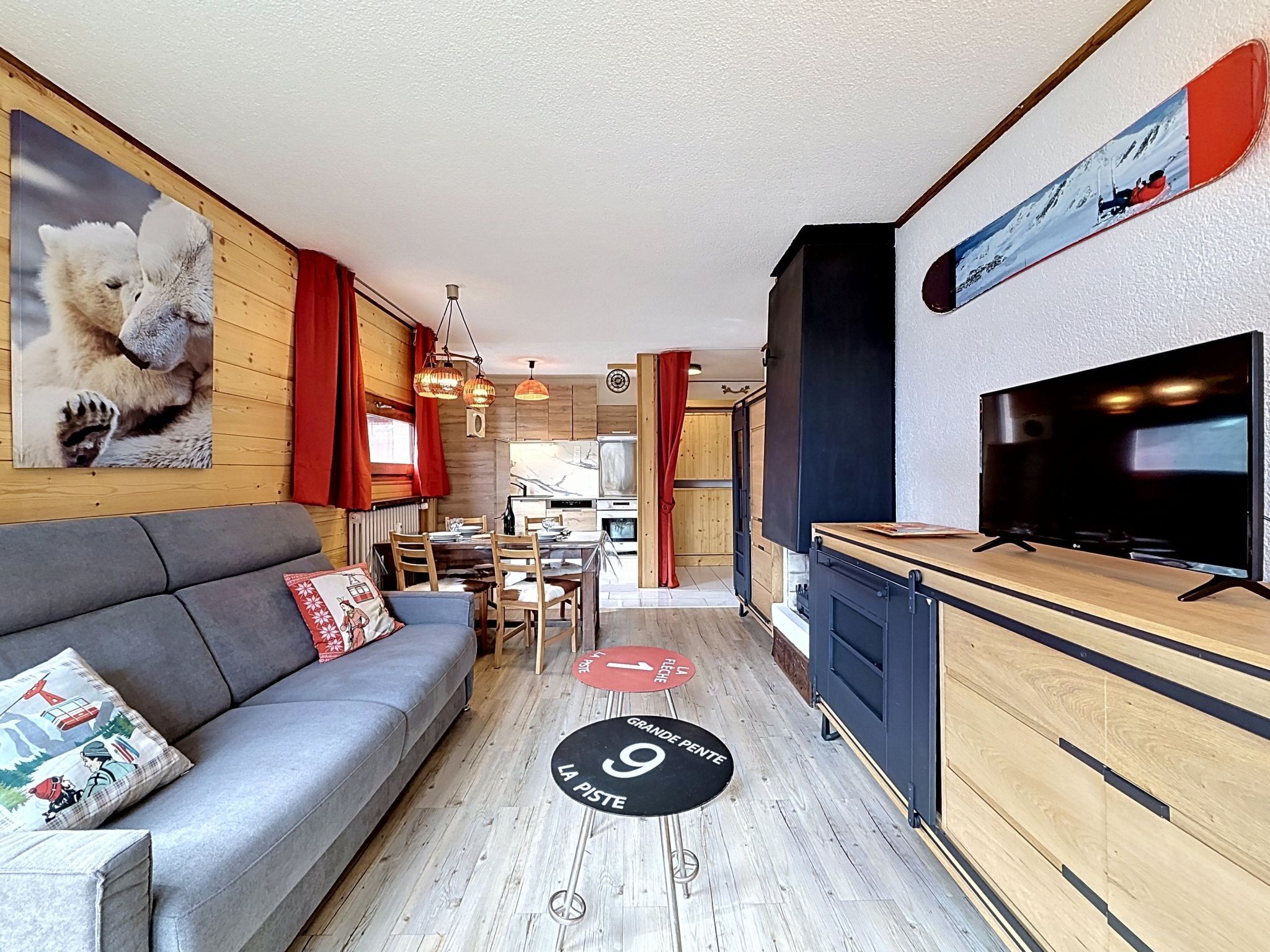 A compact living space with a sofa, dining table, kitchen area, and a television.