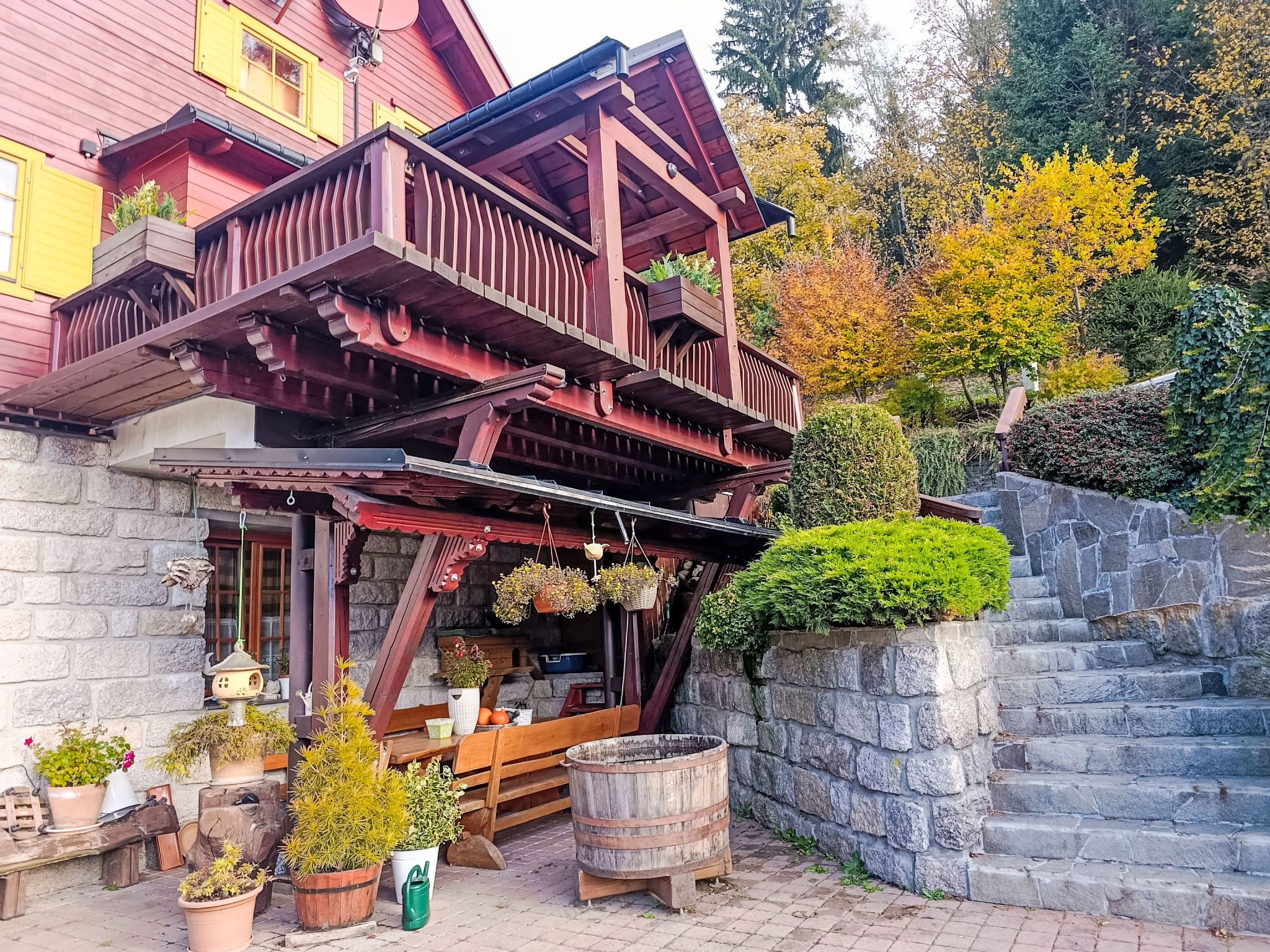 A wooden building with a balcony, stone steps, and potted plants.
