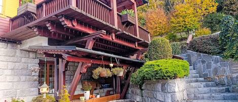 A wooden building with a balcony, stone steps, and potted plants.