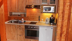 Eine kleine Küche mit Holzausstattung, einer Mikrowelle, einem Herd und einem Kühlschrank.