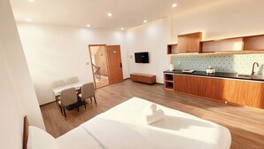 A modern hotel room with a bed, a small dining table, a kitchenette, and a TV. - Min Sweet Home 2 (Da Nang)