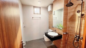 A modern bathroom with a wooden vanity, a glass shower enclosure, and a small window. - Min Sweet Home 2 (Da Nang)