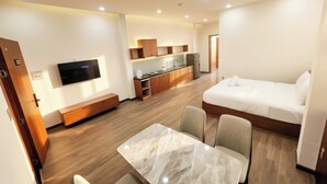 A modern hotel room with a bed, a TV, a dining area, and a kitchenette. - Min Sweet Home 2 (Da Nang)