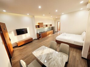 A modern hotel room with a bed, a TV, a dining area, and a kitchenette. - Min Sweet Home-Direct View of fireworks (Da Nang)
