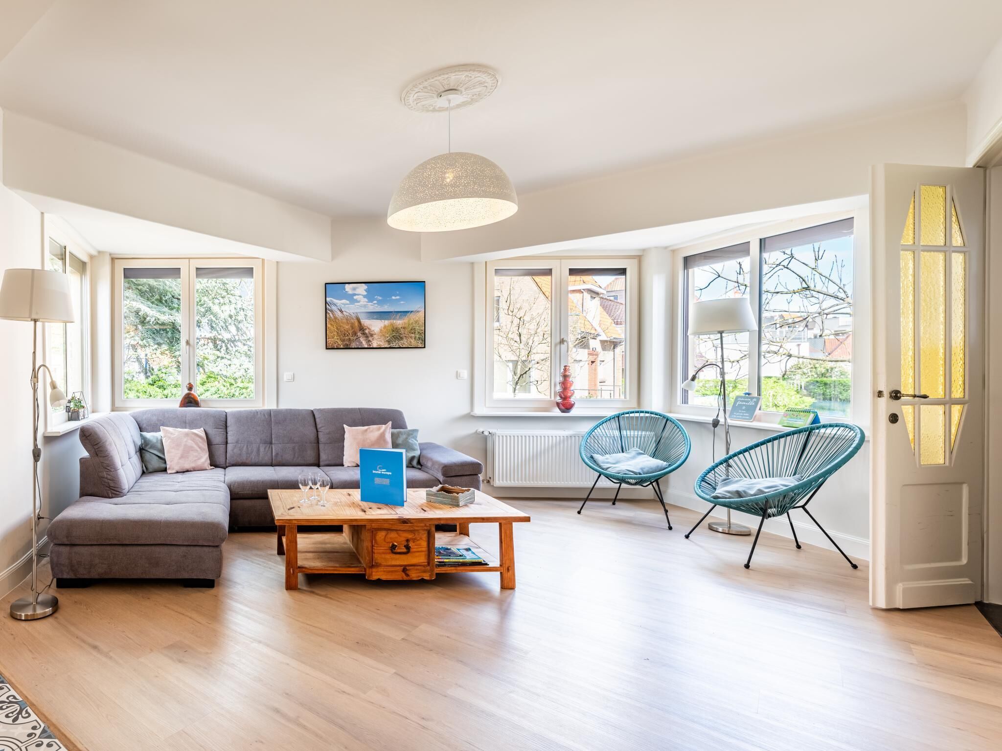 Un salon moderne avec un canapé gris, une table basse en bois et deux fauteuils bleus.