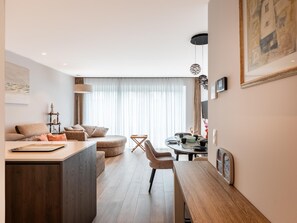 Ein modernes Wohnzimmer mit einer Couch, einem Esstisch und einer Küchenzeile.