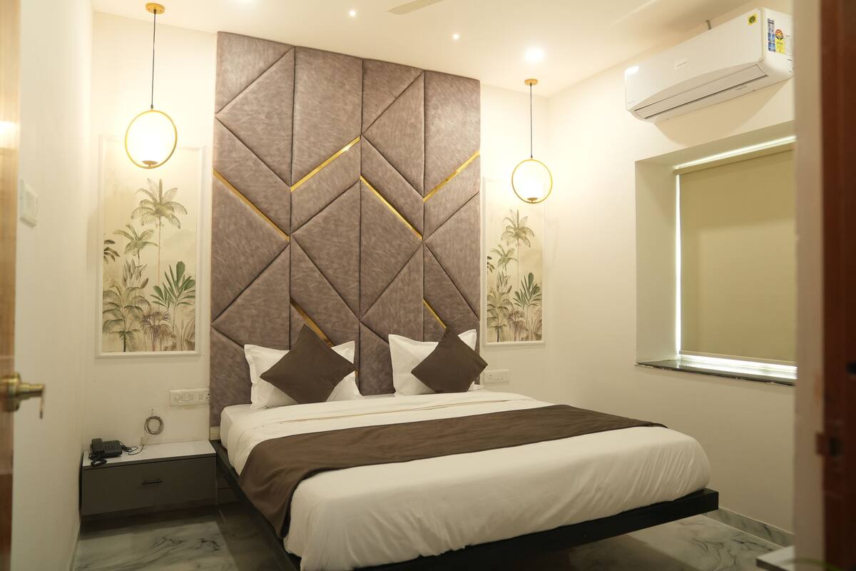A bedroom with a bed, nightstand, wall art, and an air conditioning unit.