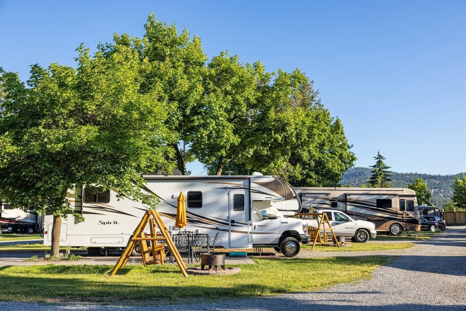 A campsite with RVs, trees, and a clear sky.