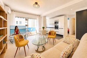 A modern living room with a sofa, chairs, a glass coffee table, and a television. - Frgk Alexander III Elegant 1-Bedroom Apartment with Terrace in Palm Beach (Cannes)