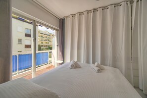 Ein Hotelzimmer mit einem großen Bett, einem Balkon und Blick auf Gebäude.