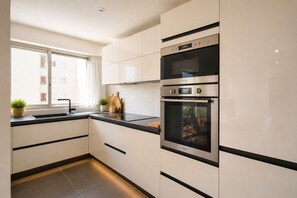 Eine moderne Küche mit weißen Schränken, einer schwarzen Arbeitsplatte und einem eingebauten Backofen.