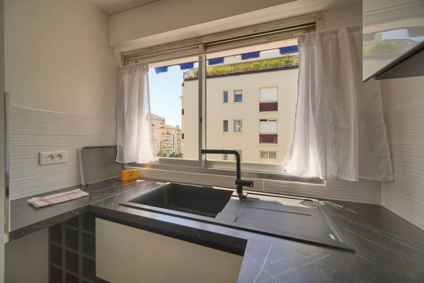 Una cocina compacta con ventana, un lavamanos y una encimera.