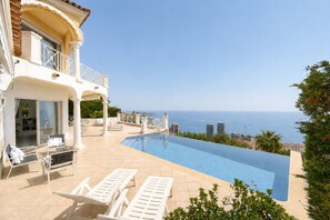 A poolside area with lounge chairs, a clear view of the sea, and a building with a balcony. - FRGK Magnificent See View Villa with Monaco backgr (Beausoleil)