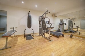 Ett gym med träningsredskap, en boxningssäck och en spegel på väggen.