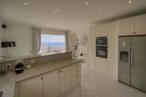 A modern kitchen with white cabinets, a granite countertop, a built-in oven, and a refrigerator. - FRGK Magnificent See View Villa with Monaco backgr (Beausoleil)
