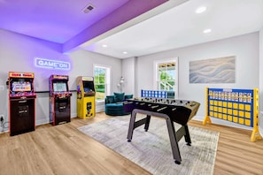 Une salle avec des jeux d’arcade, une table de baby-foot et un présentoir pour les balles de baby-foot.
