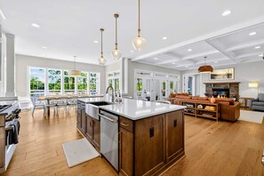 Una cocina amplia con una isla grande, armarios de madera e iluminación colgante.