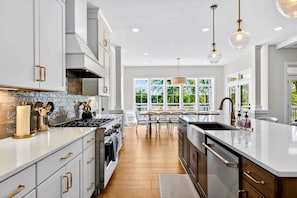Una cocina moderna con armarios blancos, una isla central y vistas al exterior.