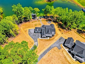 Vue aérienne d’un quartier résidentiel avec une grande maison, une construction plus petite et une jetée qui s’avance dans un lac.