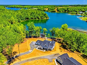 Vista aérea de una zona residencial con un lago grande, rodeada de árboles frondosos y viviendas.