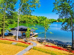 Una cabaña junto al lago con un muelle, rodeada de árboles y una vista despejada del lago.