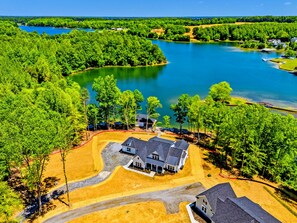 A large house with a driveway and a lake in the background. - NEW Lakefront Lake Anna, Beach, Dock, Hot Tub (Mineral)