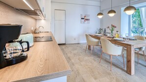 Eine moderne Küche mit Kaffeemaschine, Spüle und Essbereich mit Holztisch und Stühlen.