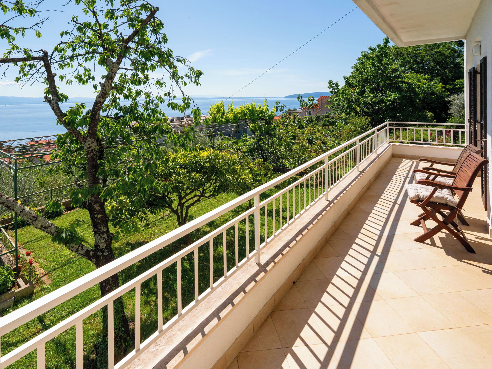 Ein Balkon mit Blick auf ein Gewässer, Grünflächen und eine ferne Stadt.