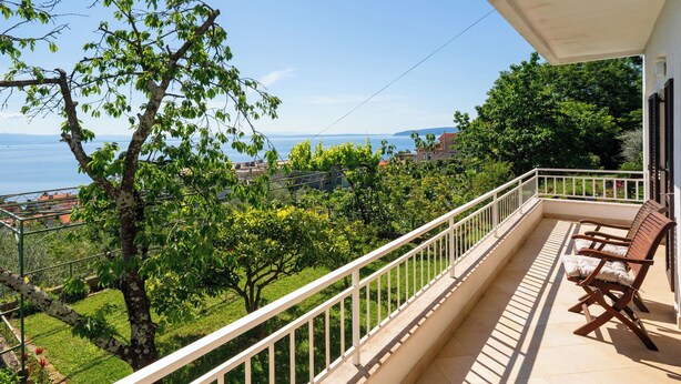Ein Balkon mit Blick auf ein Gewässer, Gr ünflächen und eine ferne Stadt.