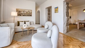 Ein modernes Wohnzimmer mit einer Couch, Sesseln, einem Couchtisch und einem Essbereich mit Tisch und Stühlen.