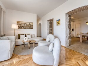 A modern living room with a sofa, armchairs, a coffee table, and a dining area with a table and chairs. - Apartment Emil by Interhome (Lovran)