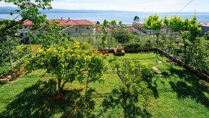 Ein Garten mit einer Pergola, einem kleinen Teich und Blick auf einen See und ferne Berge.