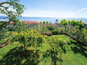 A garden with a pergola, a small pond, and a view of a lake and distant mountains. - Apartment Emil by Interhome (Lovran)