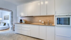 Eine moderne Küche mit weißen Schränken, einer Holzarbeitsplatte und einem eingebauten Backofen.