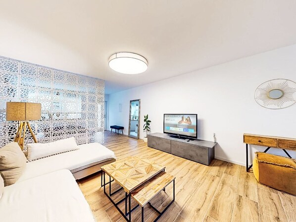 Ein modernes Wohnzimmer mit einer Couch, Couchtisch, Fernseher und Dekorationselementen.