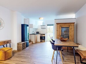 A modern kitchen with a microwave, sink, and wooden cabinets. There is a dining area with a table and chairs. - Renovierte Erdgeschosswohnung by Interhome (Simmersfeld)