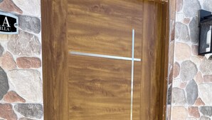 Eine Holztür mit einer Steinwand, einer Metallklinke und einem kleinen Außenbereich mit einer Bank.