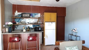 Une cuisine de taille réduite équipée d’un réfrigérateur, de tabourets de bar et d’un four à micro-ondes.