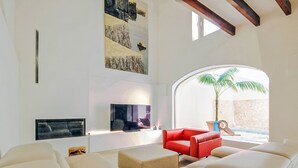 Ein modernes Wohnzimmer mit großem Fernseher, einem roten Sofa und Blick auf einen Pool.