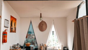 Une cuisine de taille réduite, équipée d’un réfrigérateur, d’un plan de travail en bois, d’un luminaire suspendu et d’un tableau accroché au mur.