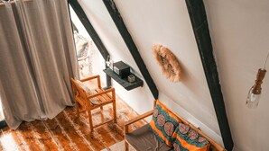Une pièce de style loft avec un plancher en bois, un canapé agrémenté de coussins à motifs, une petite table avec un plateau et un luminaire suspendu.