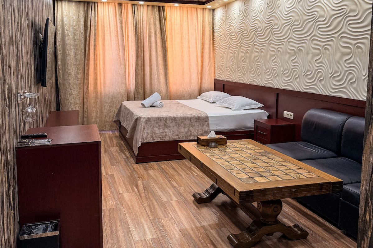 A modern room with a bed, sofa, and a wooden table.