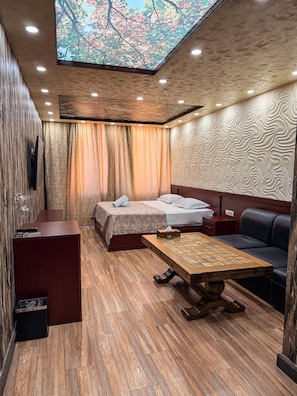 A modern room with a bed, sofa, and a wooden table. - Israel Ori Hotel (Yerevan)