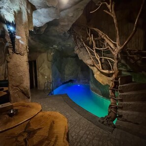 A cave-like interior with a pool, wooden furniture, and a climbing tree. - Israel Ori Hotel (Yerevan)