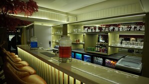 A bar area with a counter, stools, and shelves with glassware. - Trevon Twin Tree Inn (Dhanbad)
